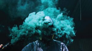 Image of man with green smoke over his face. Greenwashing.